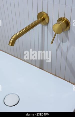 Bronze bathroom water tap in a bathroom finished with white tiles. Minimalist bathroom finish. Photographed in natural light. Stock Photo