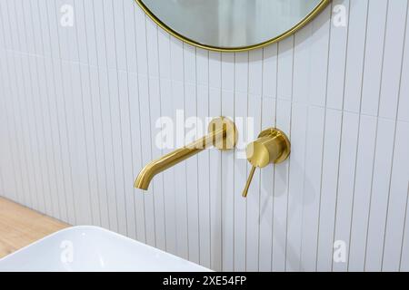 Bronze bathroom water tap in a bathroom finished with white tiles. Minimalist bathroom finish. Photographed in natural light. Stock Photo