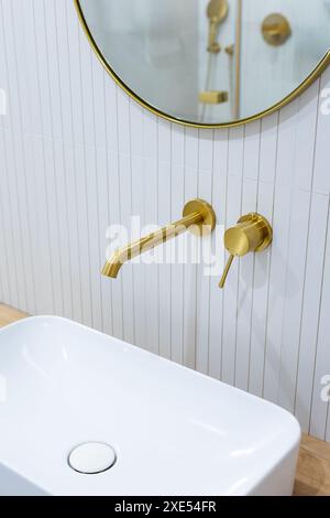 Bronze bathroom water tap in a bathroom finished with white tiles. Minimalist bathroom finish. Photographed in natural light. Stock Photo