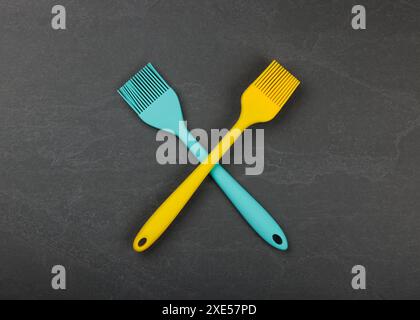 Two silicone culinary brushes on black slate board Stock Photo
