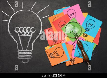 Drawn light bulbs on sheets of paper and a plastic magnifying glass Stock Photo