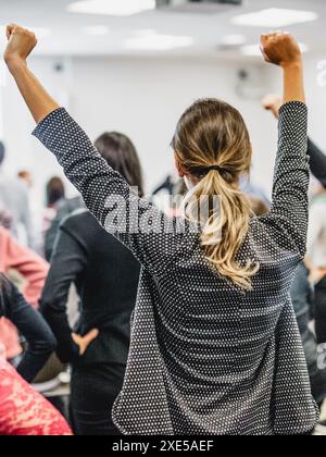 Life coaching symposium. Speaker giving interactive motivational speech at business workshop. Rear view of unrecognizable participants feeling empower Stock Photo