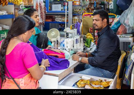 Indian tailor talking with his two female customers dress in Sari. Little India, Singapore. Stock Photo