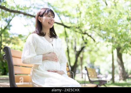 Pregnant woman sitting on a park bench Stock Photo