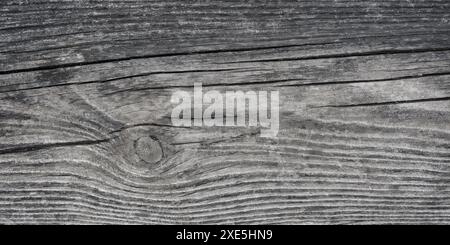 Close-up of a weathered, dark gray wood plank with visible cracks and intricate grain patterns. Timeworn Wooden Texture Stock Photo