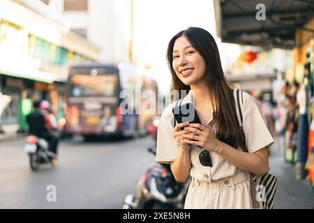 Smiling Asian woman traveller backpacker using application of taxi service app on smart phone Stock Photo
