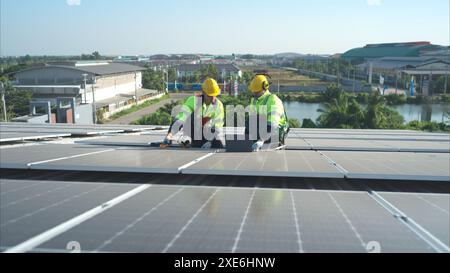 Both of technicians is installing solar panels on the roof of the warehouse to change solar energy into electrical energy for us Stock Photo