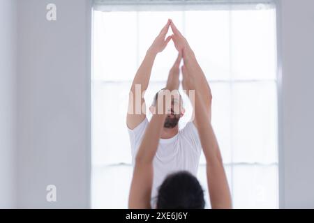 Young couple practicing yoga in a white room of studio. Stock Photo