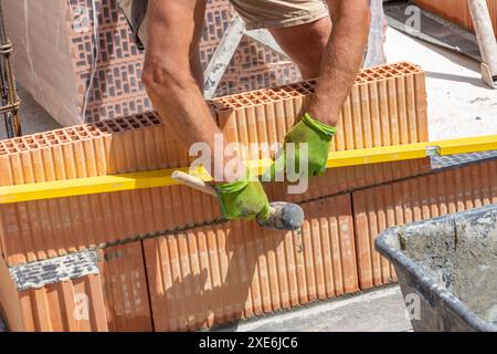 detail of cellar wall insulation at the construction site with worker building the wall using the spirit level Stock Photo