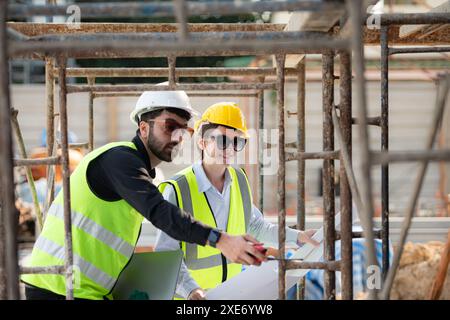 Engineer and architect working on the construction site, double-checking plans and process. Stock Photo