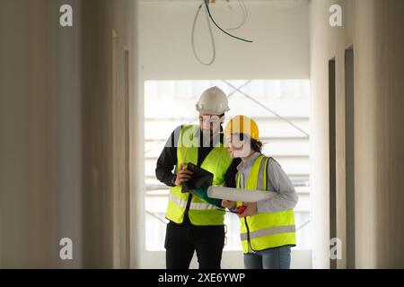 Engineer and architect working on the construction site, double-checking plans and process. Stock Photo