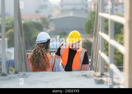 Male and female engineers working on construction site, They are inspecting the cement plaster work on the walls and balconies o Stock Photo