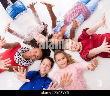 joyful teenagers lying on the floor with hands up Stock Photo