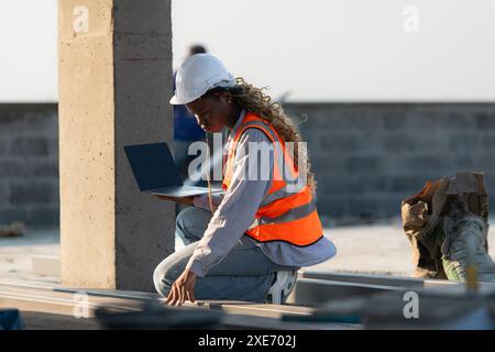 Young female architect working on a construction site with a laptop in her hands Stock Photo