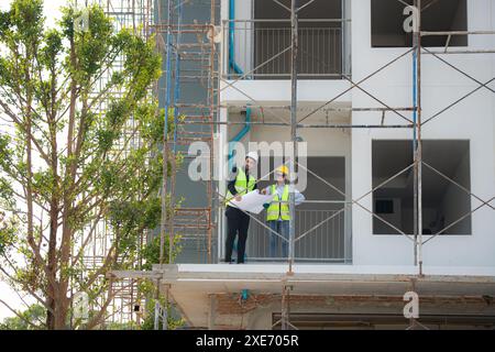 Engineer and architect working on the construction site, double-checking plans and process. Stock Photo