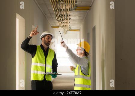 Male and female engineers working on construction site, they are monitoring the building's electrical system. Stock Photo