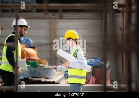 Engineer and architect working on the construction site, double-checking plans and process. Stock Photo