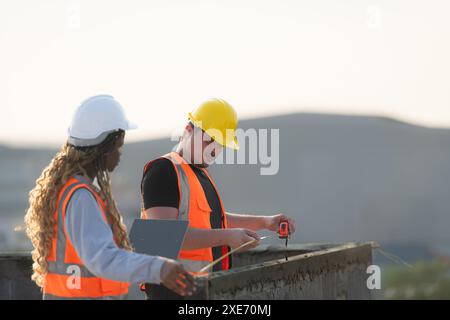 Male and female engineers working on construction site, They are inspecting the cement plaster work on the walls and balconies o Stock Photo