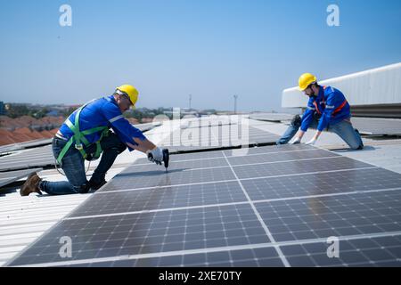 Both of technicians is installing solar panels on the roof of the warehouse to change solar energy into electrical energy for us Stock Photo