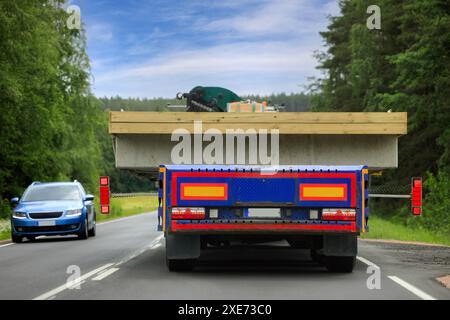 Rear view of a heavy truck and trailer transporting oversize load in highway traffic, oncoming car gives way due to the width of the transport. Stock Photo