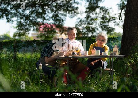 In the pottery workshop, an Asian retired couple is engaged in pottery making and clay painting activities. Stock Photo