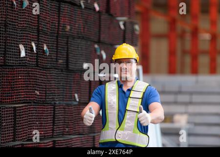 Portrait of a construction worker standing with thumbs up in front of steels material wall Stock Photo