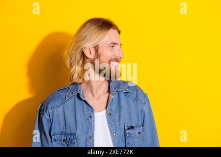 Photo portrait of handsome young male headphones look empty space smile dressed stylish denim garment isolated on yellow color background Stock Photo