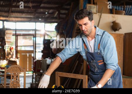 Carpenter working on laptop in his workshop at a woodworking factory Stock Photo