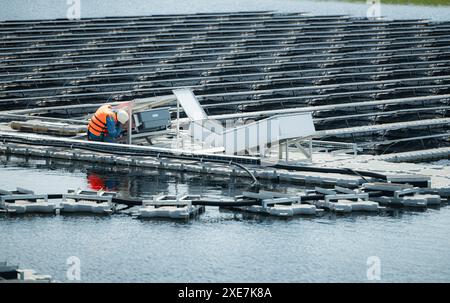 Technician currently evaluating and repairing the transmission terminals for electricity generated by solar energy in a floating Stock Photo
