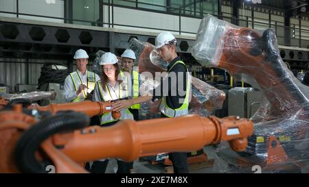 Group of engineers and technicians working together in a robotic arm factory. Inspecting robot arm before delivering to customer Stock Photo
