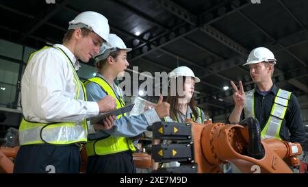 Group of engineers and technicians working together in a robotic arm factory. Inspecting robot arm before delivering to customer Stock Photo