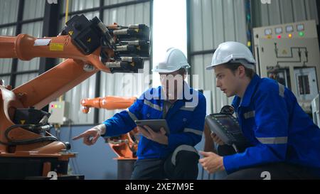 Engineer and technician working with robot arm in factory. Industry and engineering concept. Stock Photo