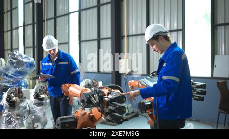 Engineer and technician working with robot arm in factory. Industry and engineering concept. Stock Photo