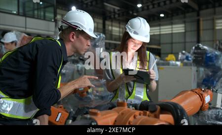 Both of engineers working together in a robotic arm factory, Robotic arm industry and engineering concept. Stock Photo