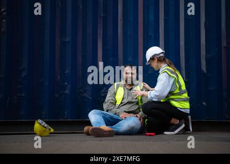 A guy worker was involved in a leg accident in a container storage yard. A colleague was using the walkie talkie to request imme Stock Photo