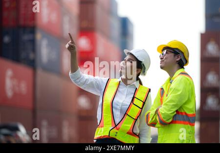 Portrait of Asian woman engineer and worker working with co-worker at overseas shipping container yard. Stock Photo