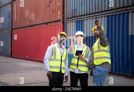 Group of engineers working with laptop in the container yard. This is a freight transportation and distribution warehouse. Stock Photo