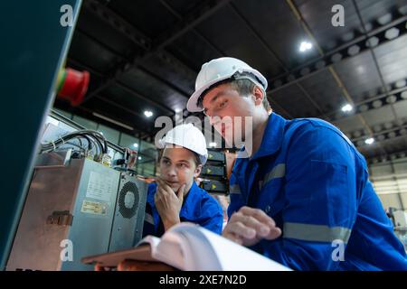 Technician working on the electrical control cabinet of robotic arm, Robotic arms industrial background Stock Photo