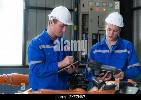 Engineer and technician working with robot arm in factory. Industry and engineering concept. Stock Photo