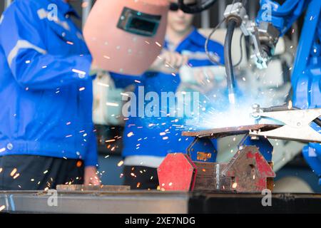 Industrial workers working with robotic arm welding machine in factory, Robotic arm welding industry and engineering concept. Stock Photo