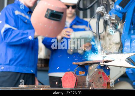 Industrial workers working with robotic arm welding machine in factory, Robotic arm welding industry and engineering concept. Stock Photo