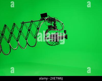Camera on telescopic jib crane against green background. Empty TV studio interior with green screen. Video production with background replacement. Stock Photo
