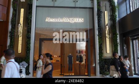 Pedestrians walk past the British multinational luxury fashion house Alexander Mcqueen logo and store in Hong Kong, China Stock Photo