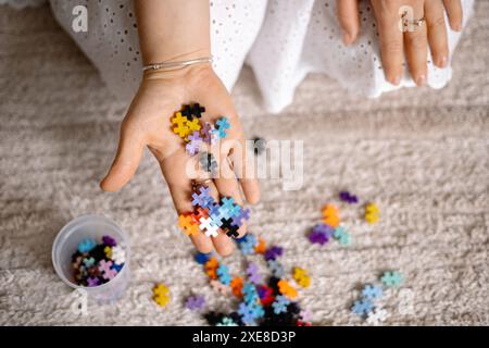 a multi-colored small puzzle set in a womans hands Stock Photo