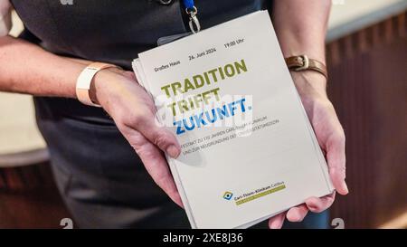 Cottbus, Germany. 26th June, 2024. An employee of the Cottbus State Theatre holds program booklets for the ceremony to mark the 110th anniversary of the Carl Thiem Clinic Cottbus under the motto 'Tradition meets future'. The 'Vereinigte Städtische und Thiemsche Heilanstalt' was inaugurated on June 27, 1914. Credit: Frank Hammerschmidt/dpa/Alamy Live News Stock Photo