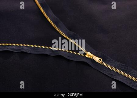 Background with open golden zipper on black fabric Stock Photo