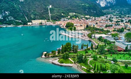 Lake Garad, Italy - June 25, 2024: Wide view with the drone from the municipality of Torbole to Riva del Garda on Lake Garda over blue, clear water. Beautiful beaches and inviting hiking trails invite you to swim and stroll. *** Weiter Blick mit der Drohne von der Gemeinde Torbole hin zu Riva del Garda am Gardasee über blauem, klarem Wasser. Schöne Strände und einladende Wanderwege laden zum Baden und Spazieren ein. Stock Photo