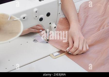 Dressmaker using sewing machine in tailor studio, modern atelier shop Stock Photo