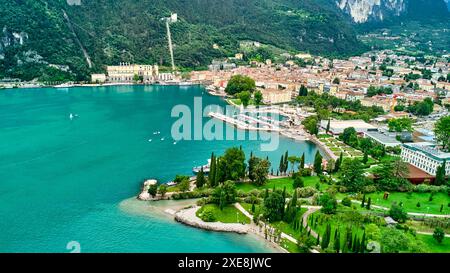 Lake Garad, Italy - June 25, 2024: Wide view with the drone from the municipality of Torbole to Riva del Garda on Lake Garda over blue, clear water. Beautiful beaches and inviting hiking trails invite you to swim and stroll. *** Weiter Blick mit der Drohne von der Gemeinde Torbole hin zu Riva del Garda am Gardasee über blauem, klarem Wasser. Schöne Strände und einladende Wanderwege laden zum Baden und Spazieren ein. Stock Photo