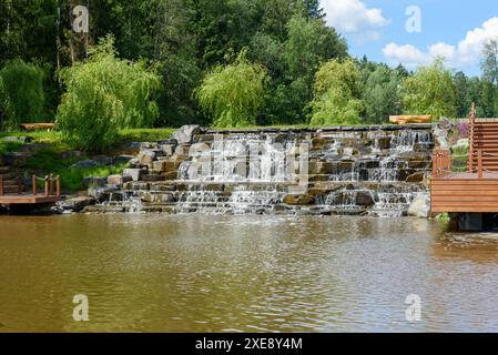 Artificial embankment with waterfall in the park on a sunny afternoon. A walk in the park. Stock Photo